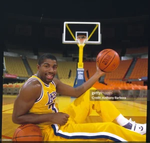 magic johnson posing in the court holding a ball in his left hand and then another ball at the right arm